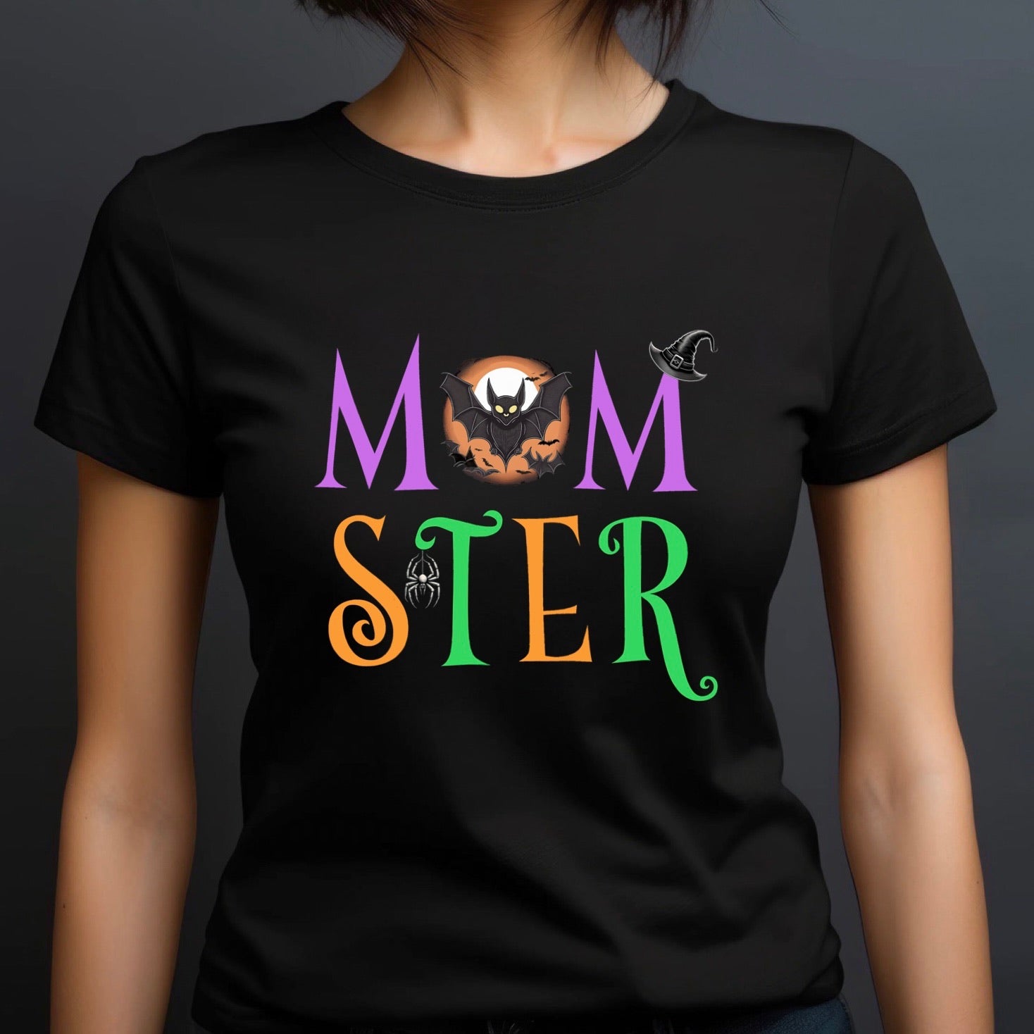 Woman wearing black Momster Halloween t-shirt with bat, witch hat, and spider in colorful design.