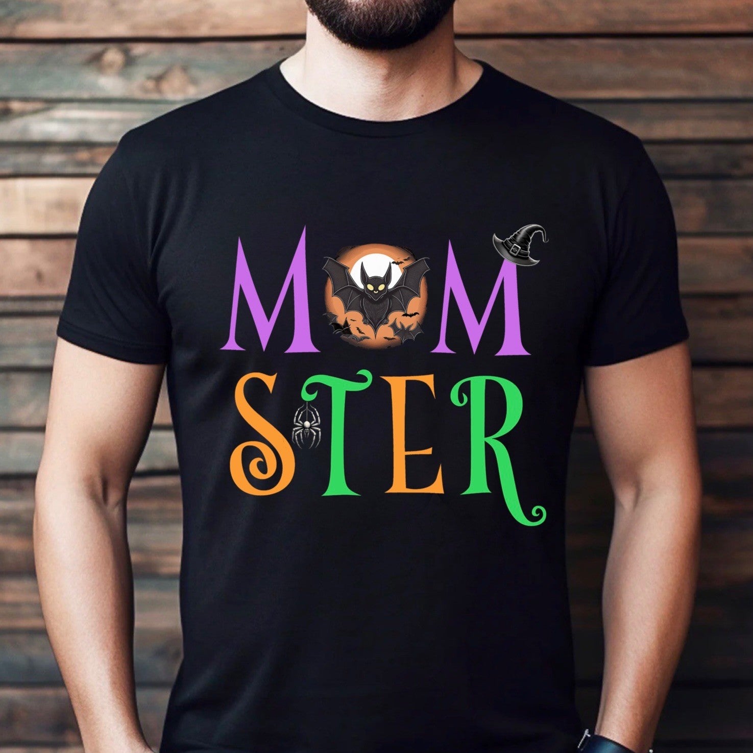 Man wearing Momster Halloween shirt with colorful letters and bat, spider, and witch hat design.