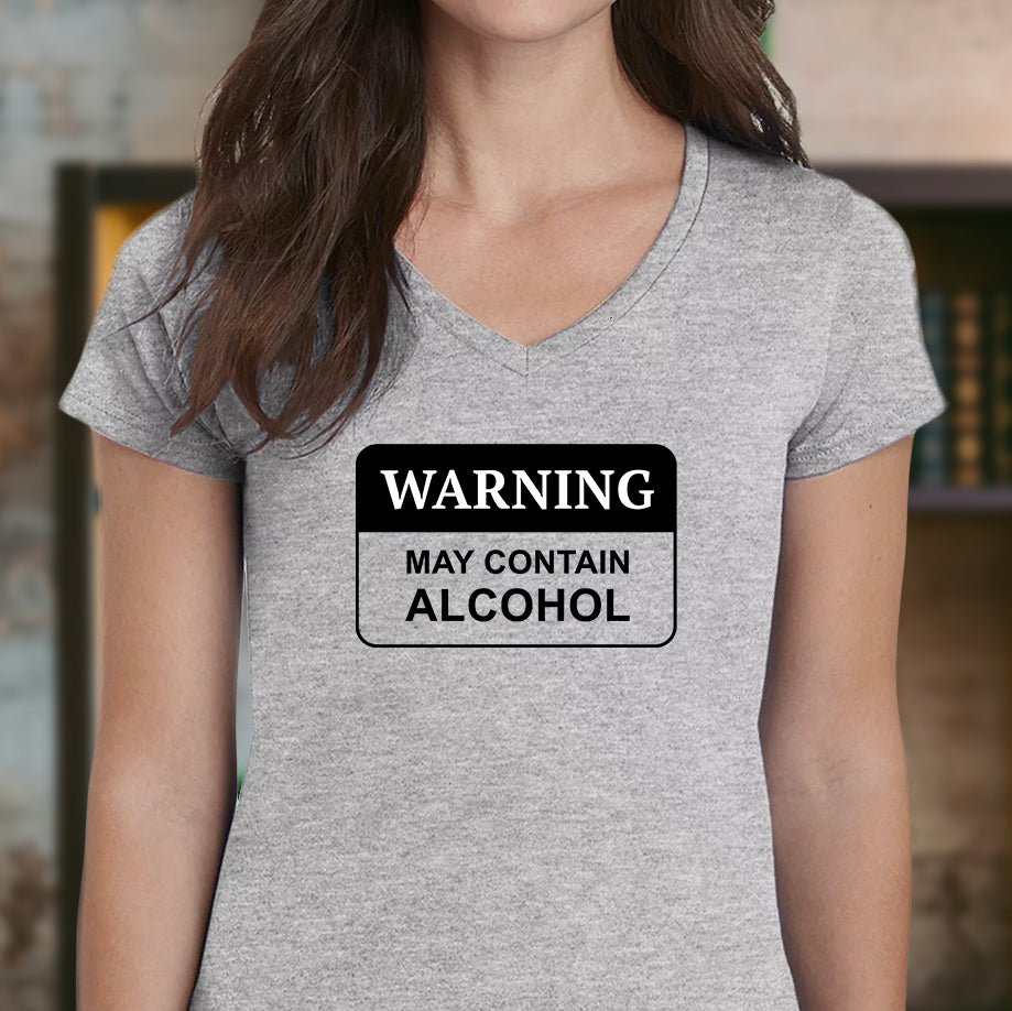 Close-up of a woman indoors wearing a fitted V-neck heather grey T-shirt with the WARNING may contain alcohol sign design