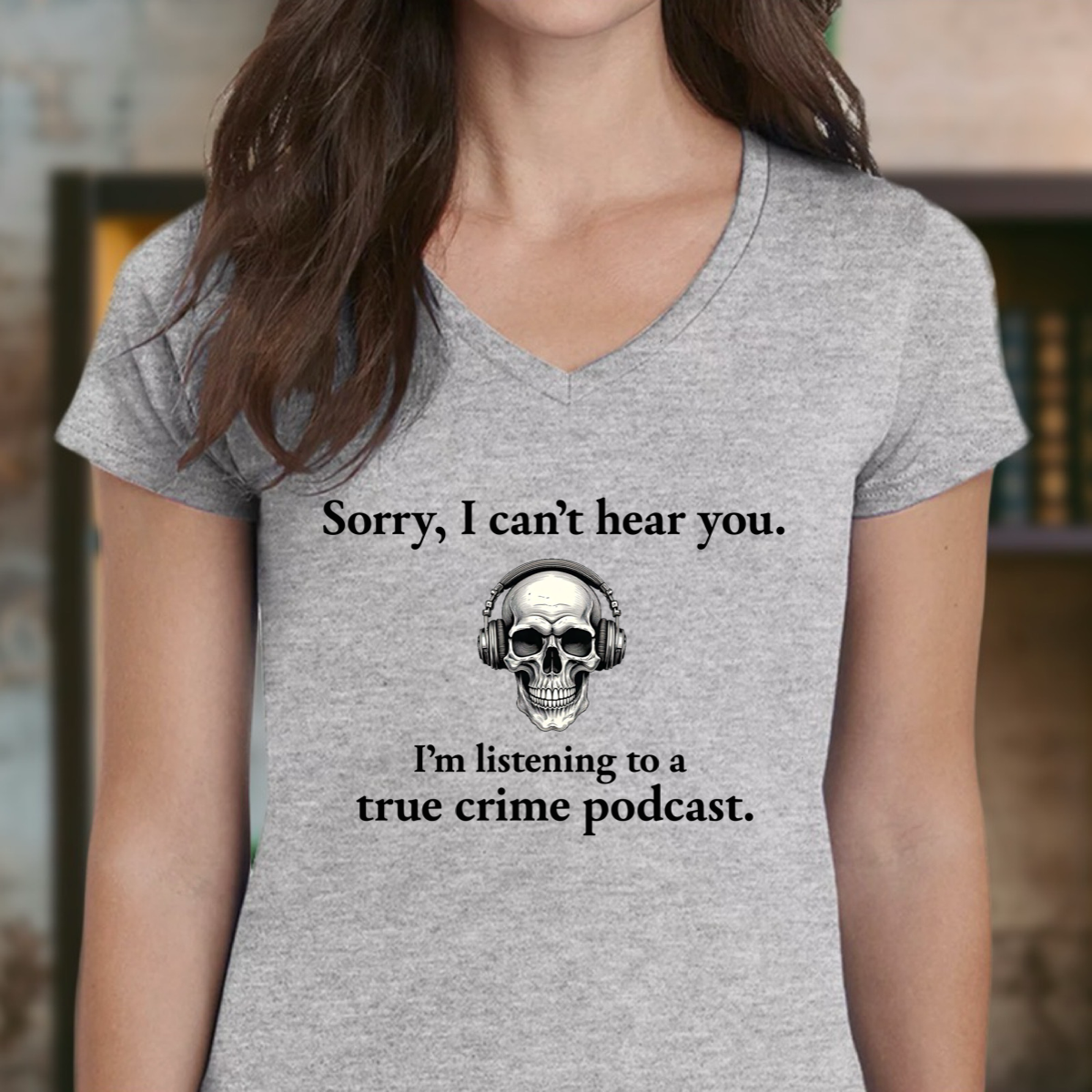 Women’s heather gray v-neck with skull headphones graphic and true crime podcast quote, front view
