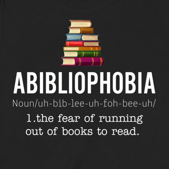 Closeup of Abibliophobia shirt design with colorful book stack and definition about fear of running out of books