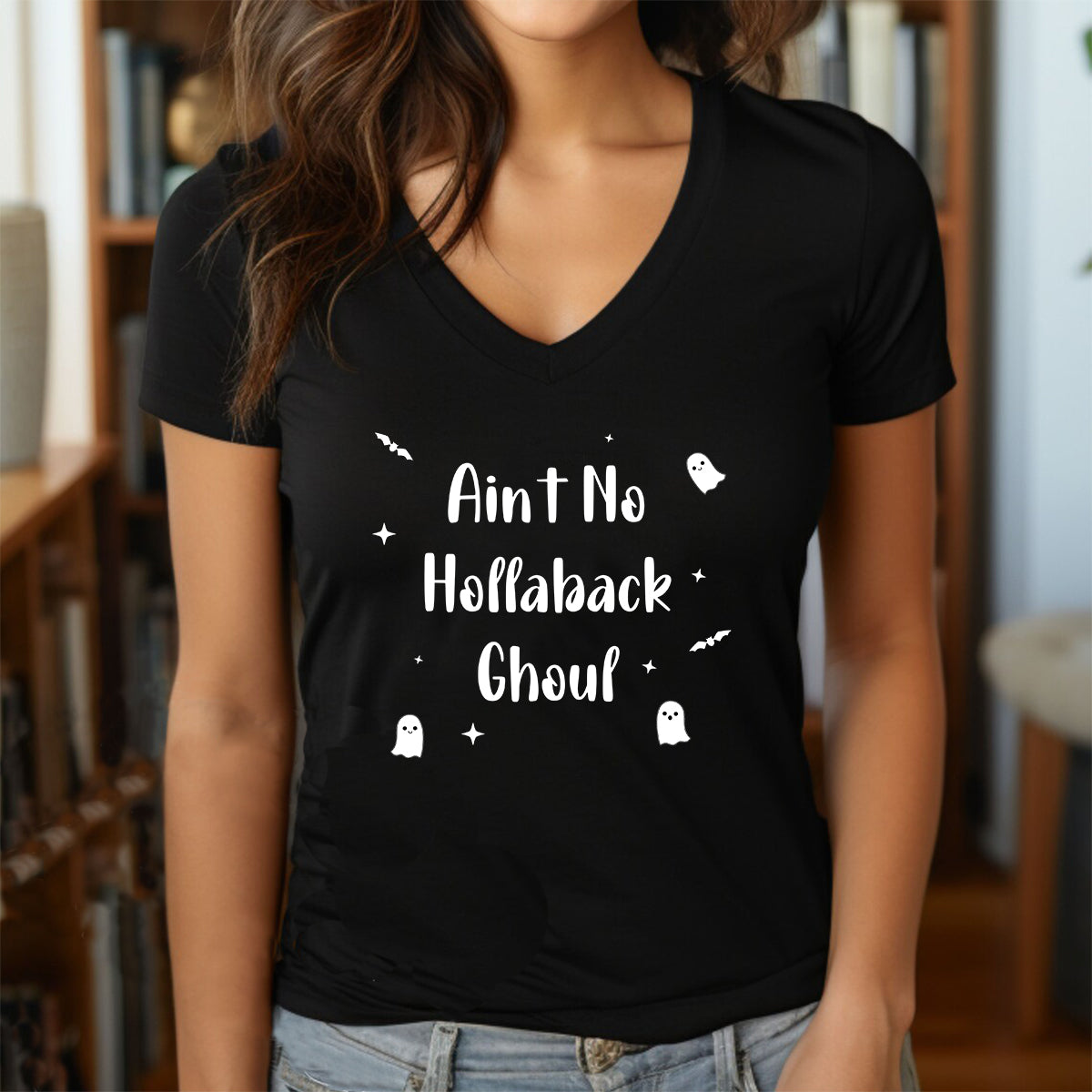 Woman wearing a black v-neck Halloween shirt with the phrase Ain’t No Hollaback Ghoul in white with ghost and bat accents.