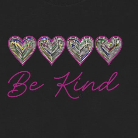 Closeup of colorful heart pattern and pink Be Kind lettering on black t-shirt