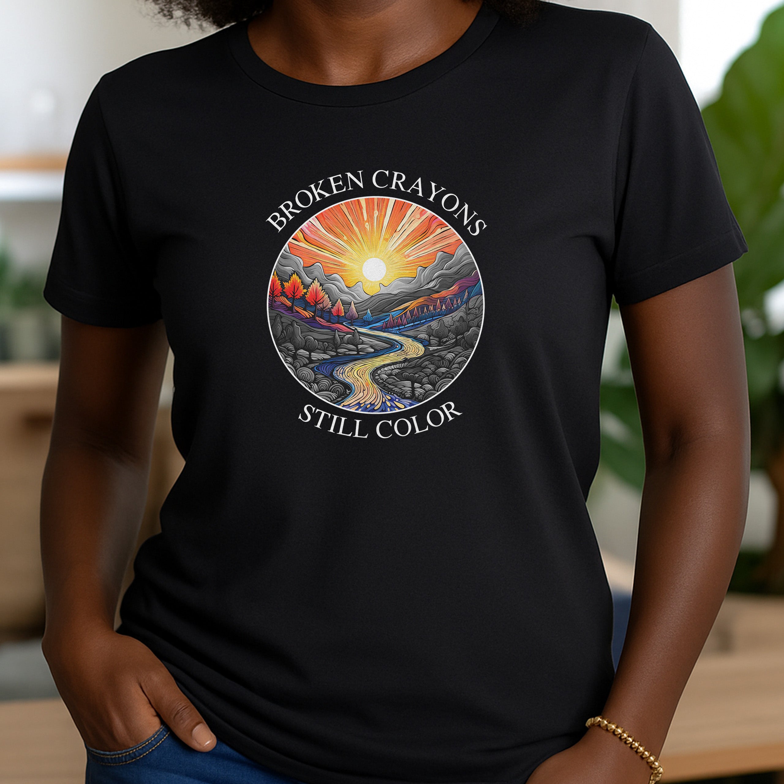 Women’s black crewneck t-shirt with motivational broken crayons still color message and colorful mountain artwork