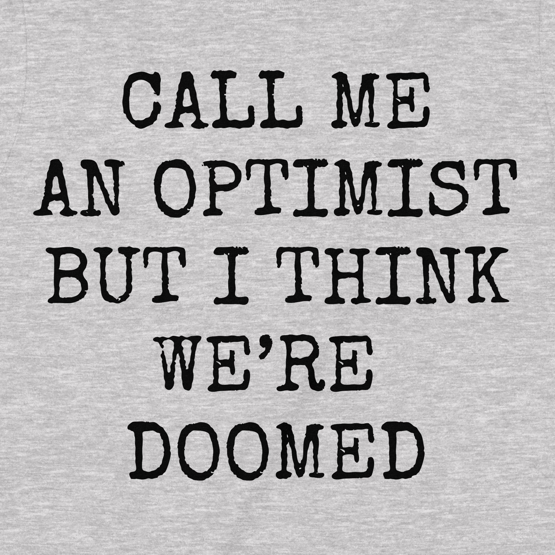 Close-up of grey t-shirt showing distressed black text call me an optimist but I think we’re doomed