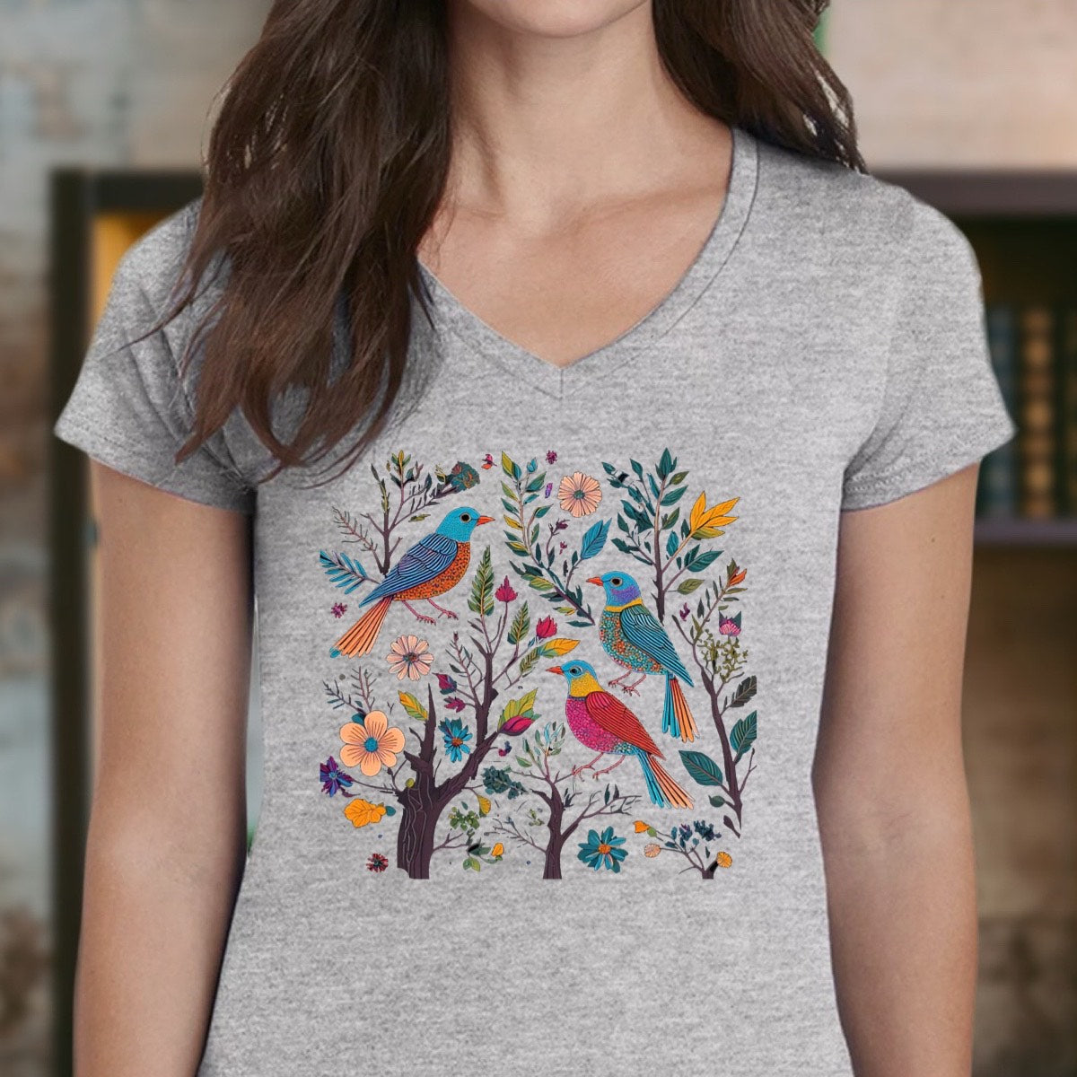 Woman wearing heather gray v-neck t-shirt with colorful songbirds and floral illustration, front view