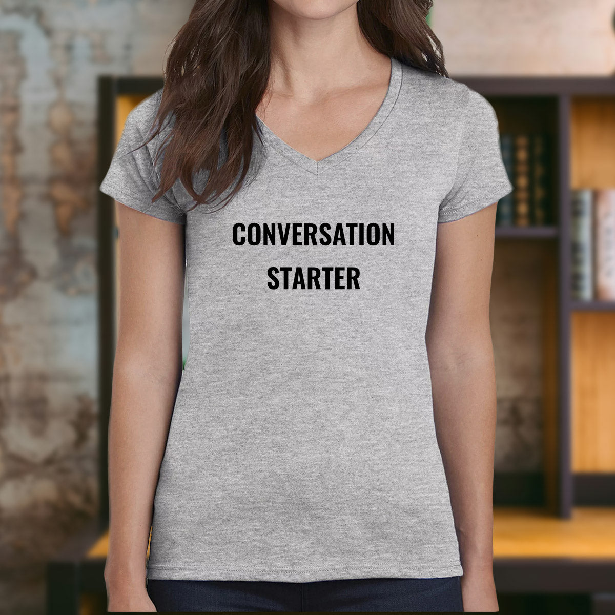 Woman wearing heather gray v-neck t-shirt with black “Conversation Starter” slogan.