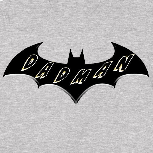 Closeup of Dadman superhero bat logo in black with bold yellow Dadman lettering on grey cotton shirt.