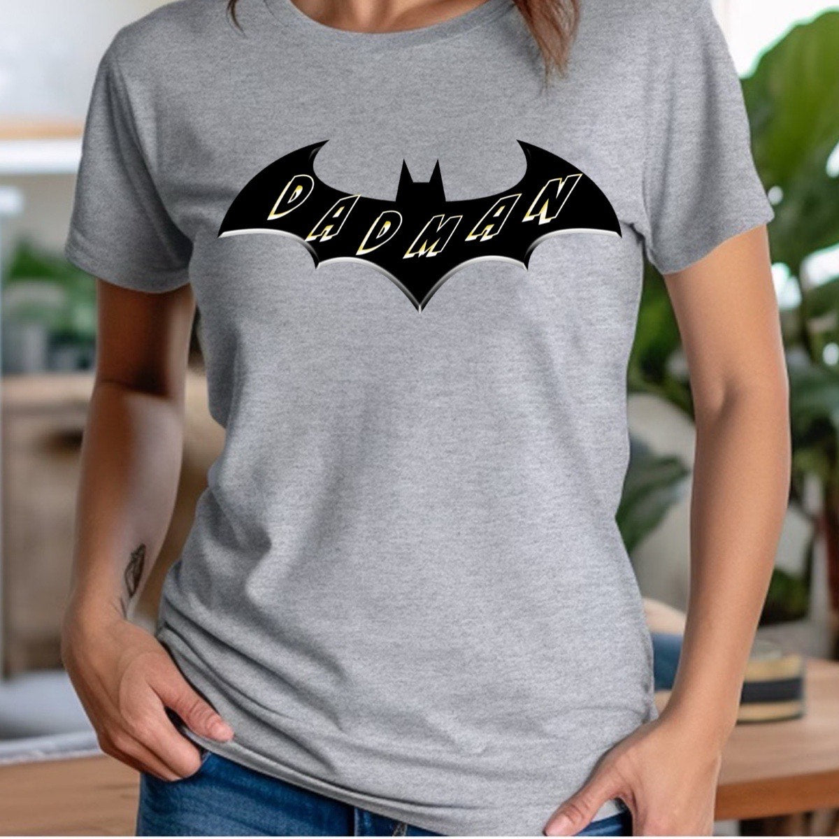 Woman wearing grey crew neck Dadman t-shirt with bold black bat logo and yellow Dadman lettering.