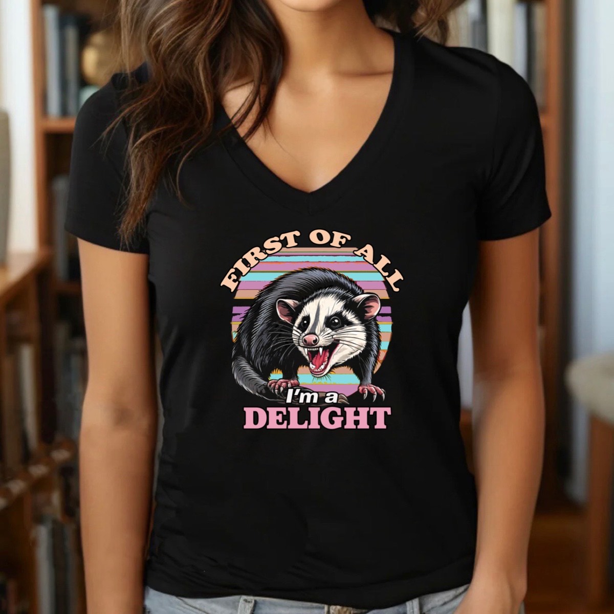 Woman wearing black v-neck t-shirt with opossum graphic, retro stripes, and text First of all I’m a delight