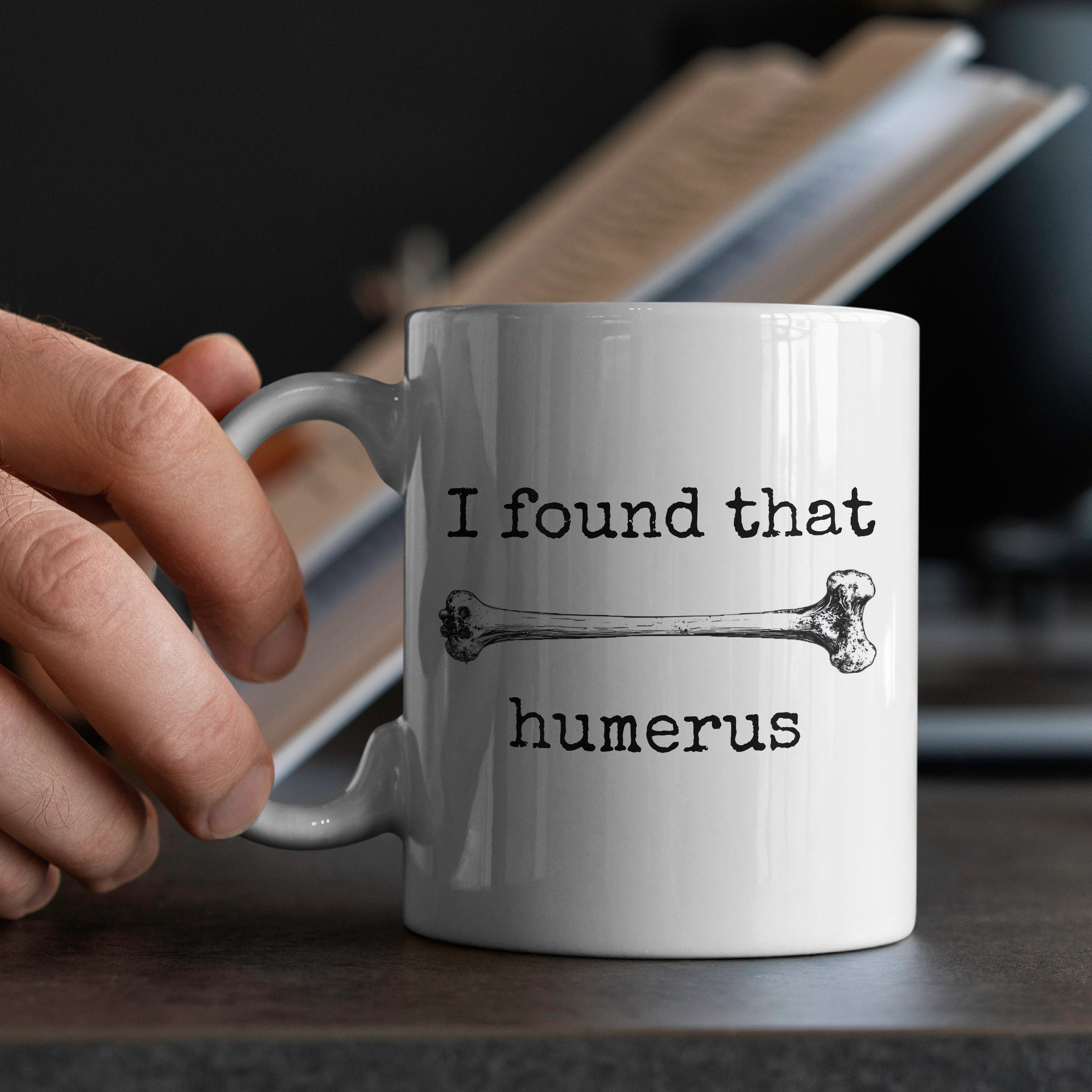 White ceramic mug in hands with funny skeleton design i found that humerus perfect novelty gift