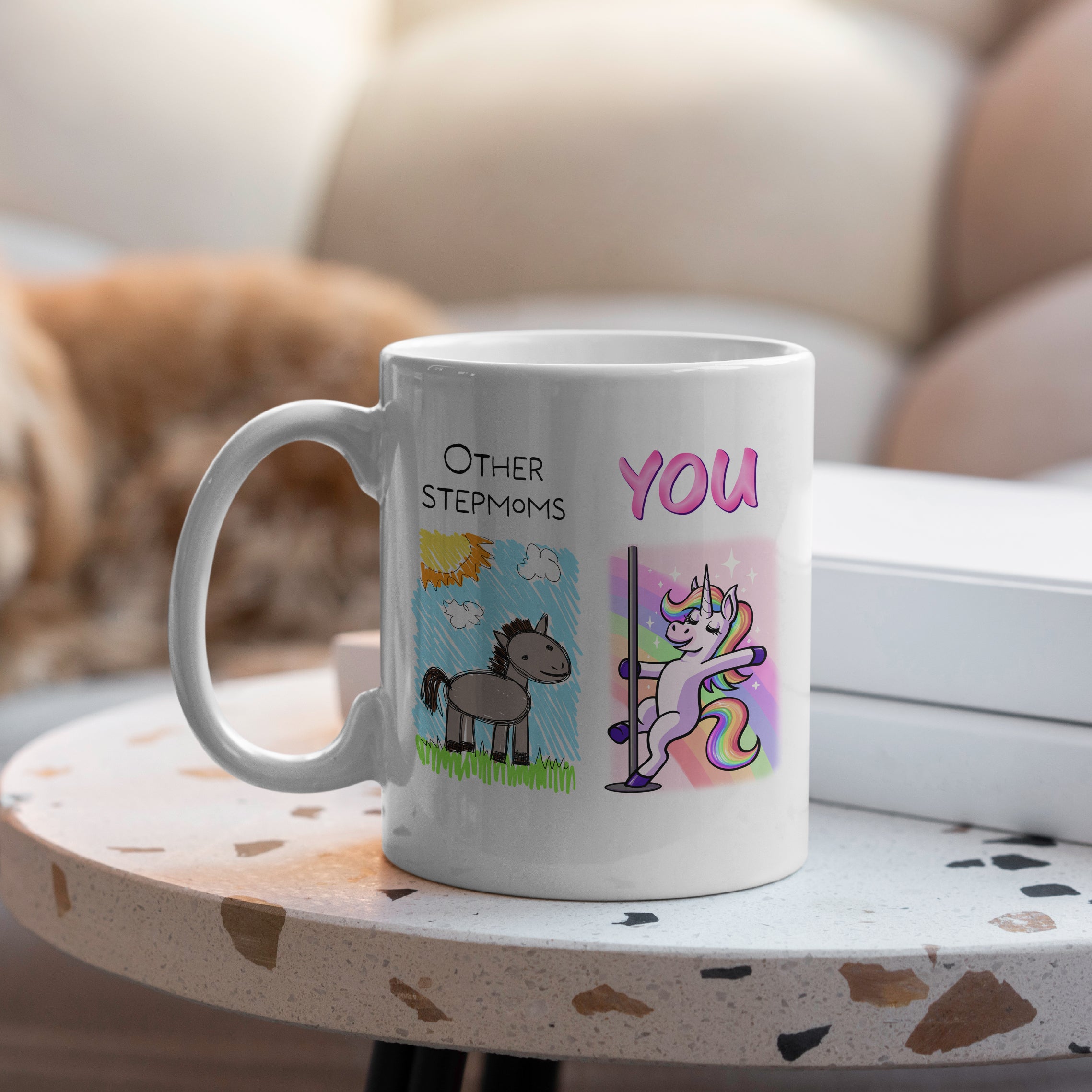 White ceramic stepmoms mug with unicorn vs cartoon horse doodle on table
