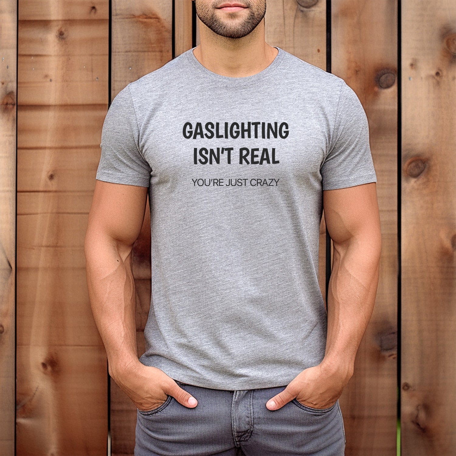 Man wearing gray crew neck t-shirt with humorous quote gaslighting isn’t real you’re just crazy