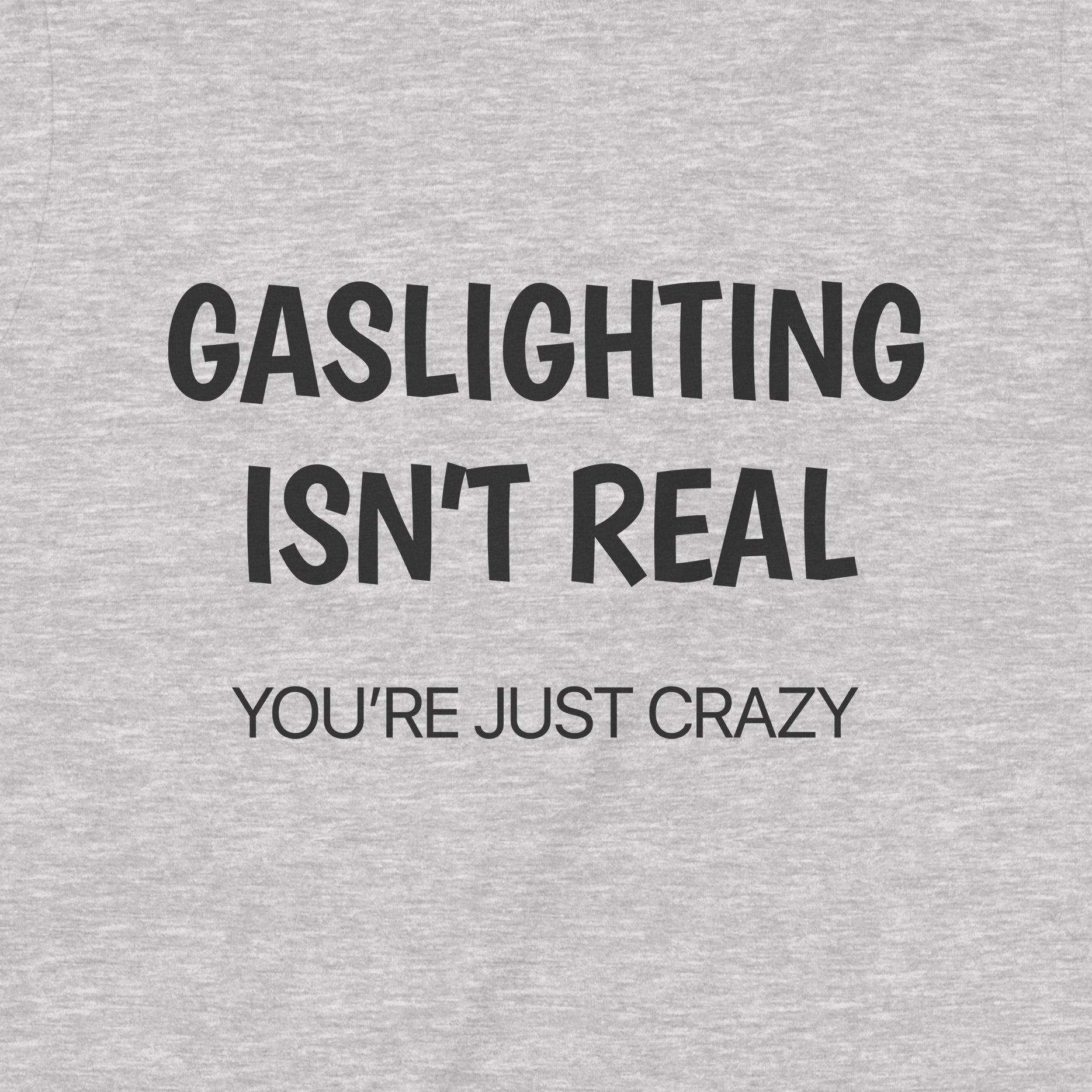 Closeup of gray shirt with bold black lettering gaslighting isn’t real you’re just crazy
