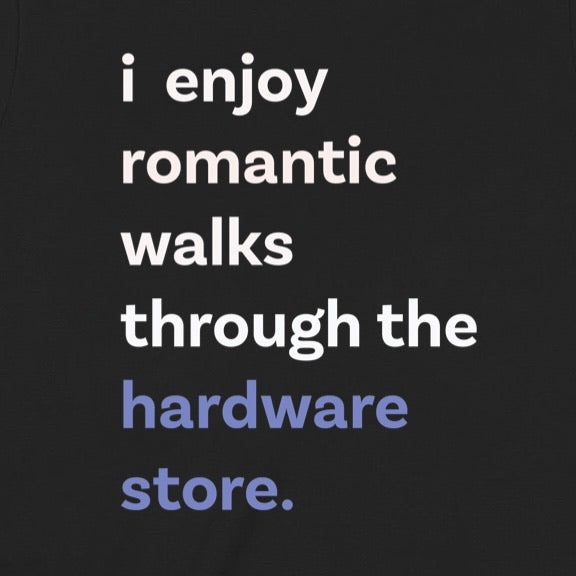Closeup of black t-shirt showing text i enjoy romantic walks through the hardware store in bold white and blue