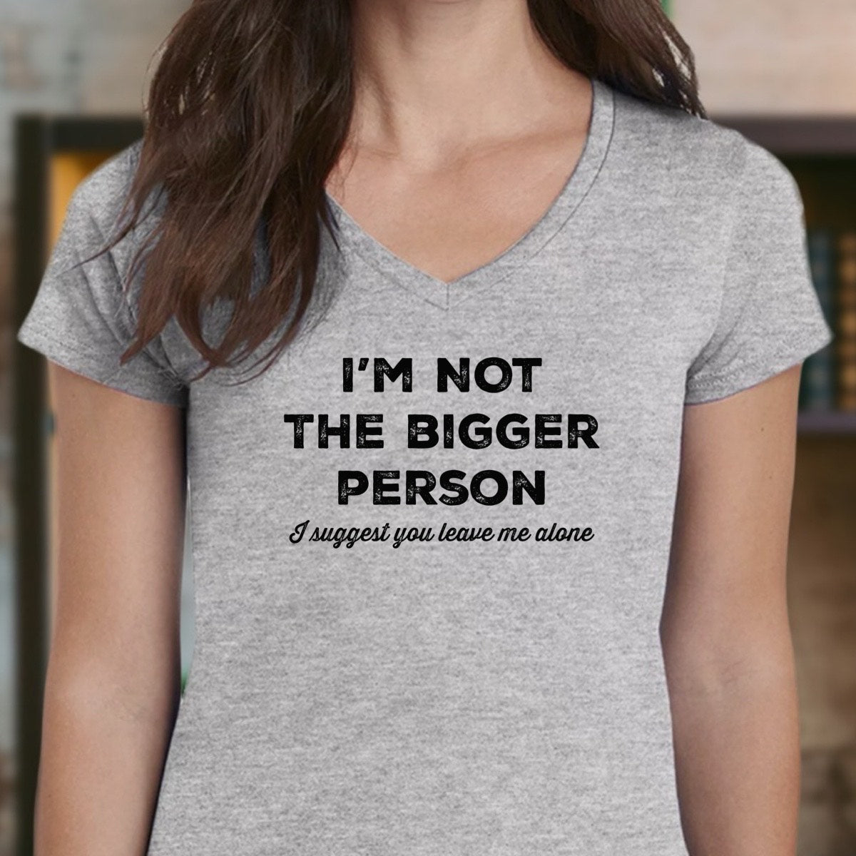 Woman wearing heather gray v-neck t-shirt reading I’m not the bigger person, I suggest you leave me alone, front view