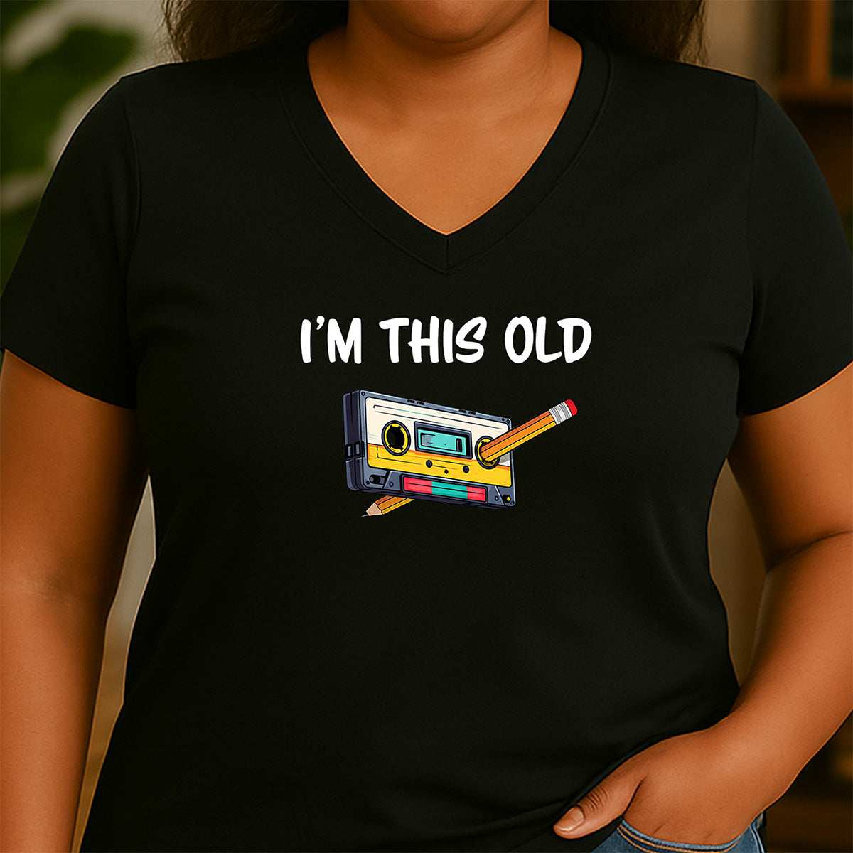 Woman wearing black v-neck shirt with retro cassette tape illustration and I’m this old quote