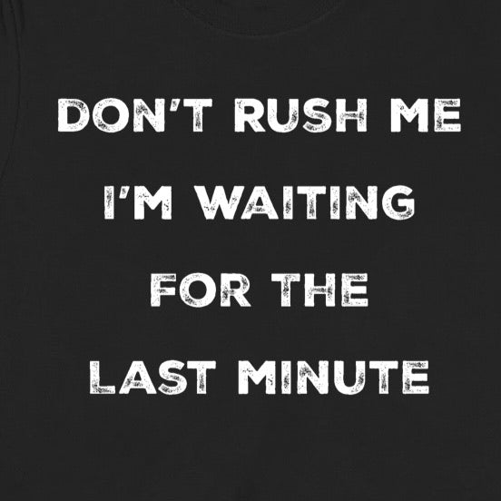 Closeup of black funny procrastination shirt with white distressed text saying don't rush me I'm waiting