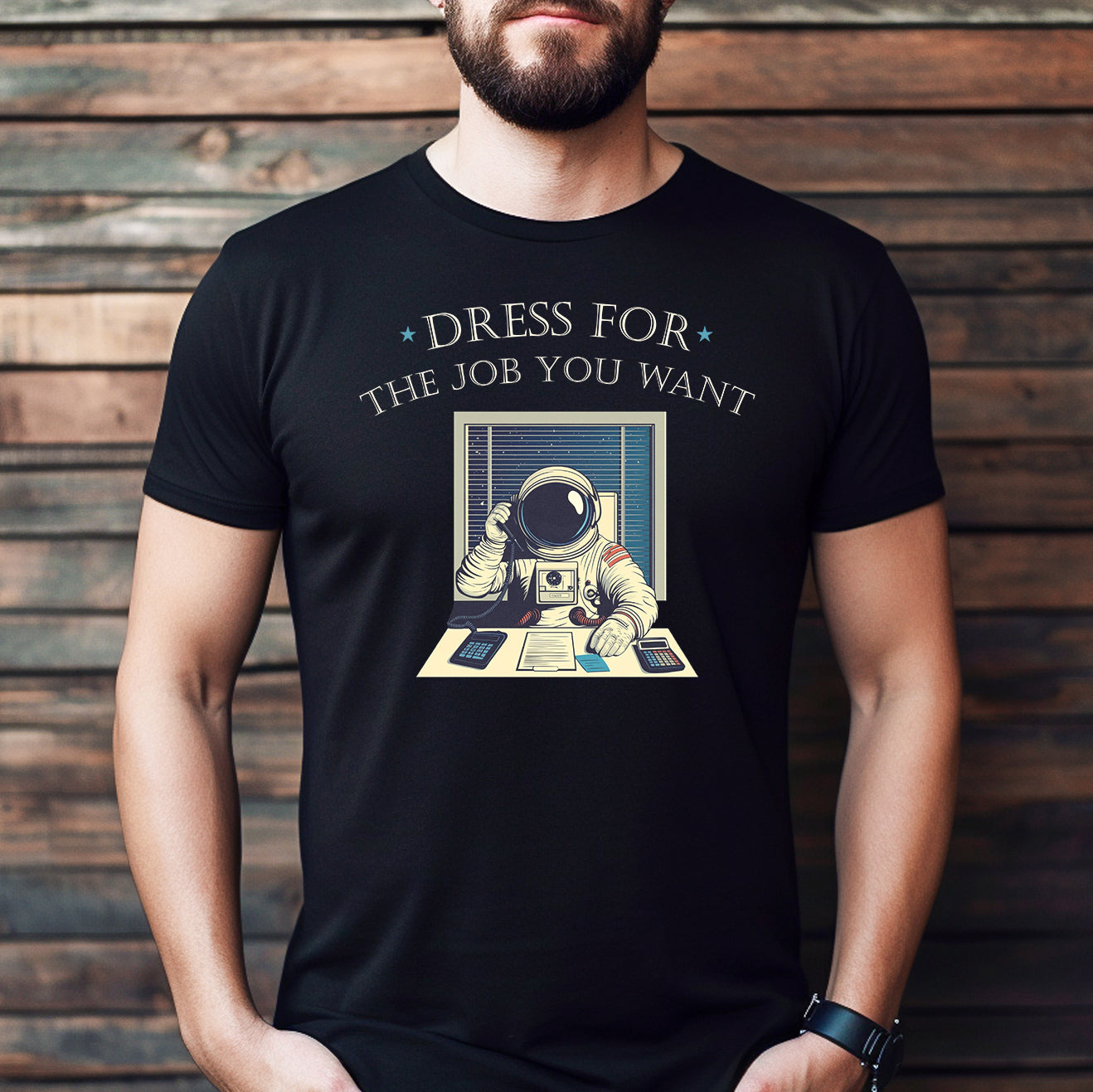 Man wearing black crew neck shirt with astronaut office design and motivational text dress for the job you want