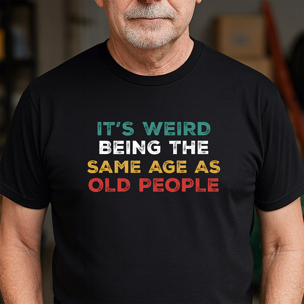 Man wearing black graphic tee reading It’s Weird Being The Same Age As Old People; retro colors; funny birthday shirt for adults