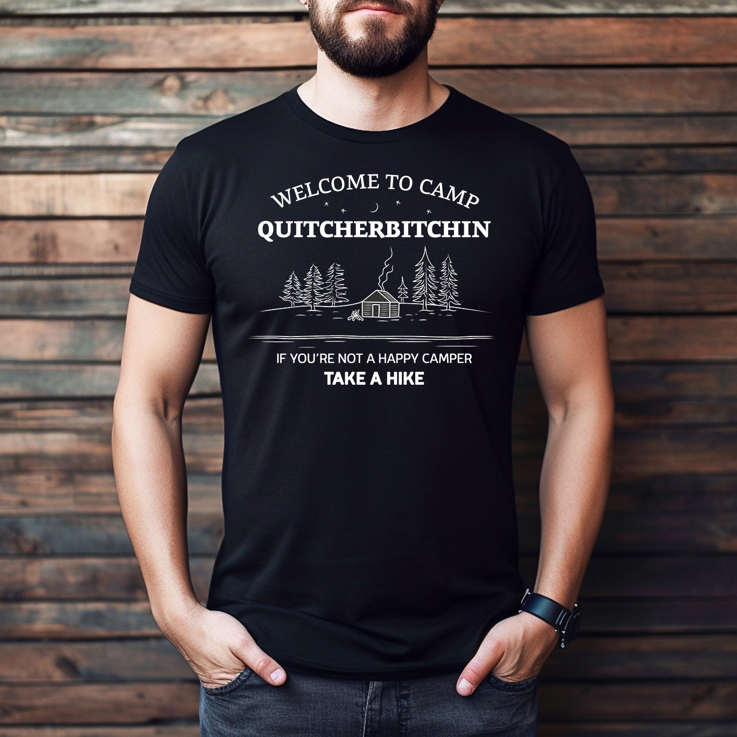 Man wearing black Camp Quitcherbitchin T-shirt with cabin and pine trees graphic, funny camping shirt