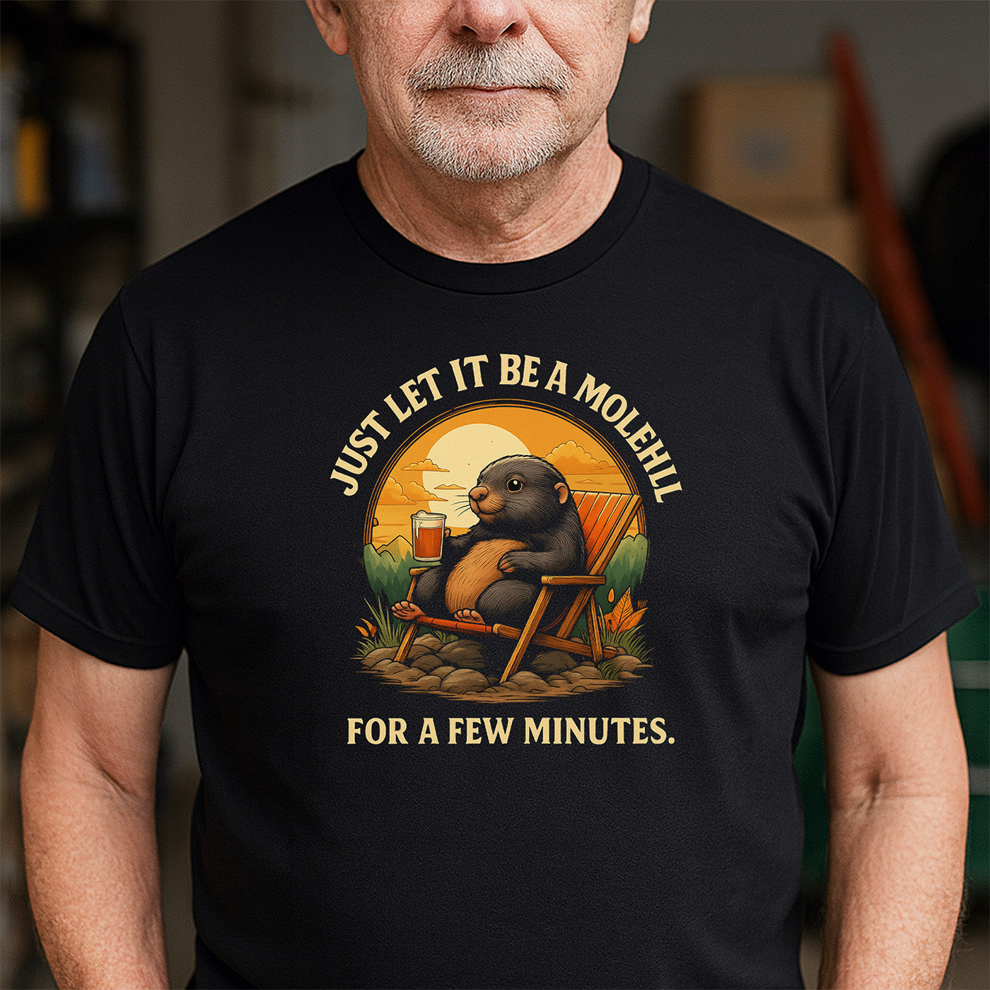 older man wearing black t-shirt with mole relaxing design and phrase just let it be a molehill for a few minutes