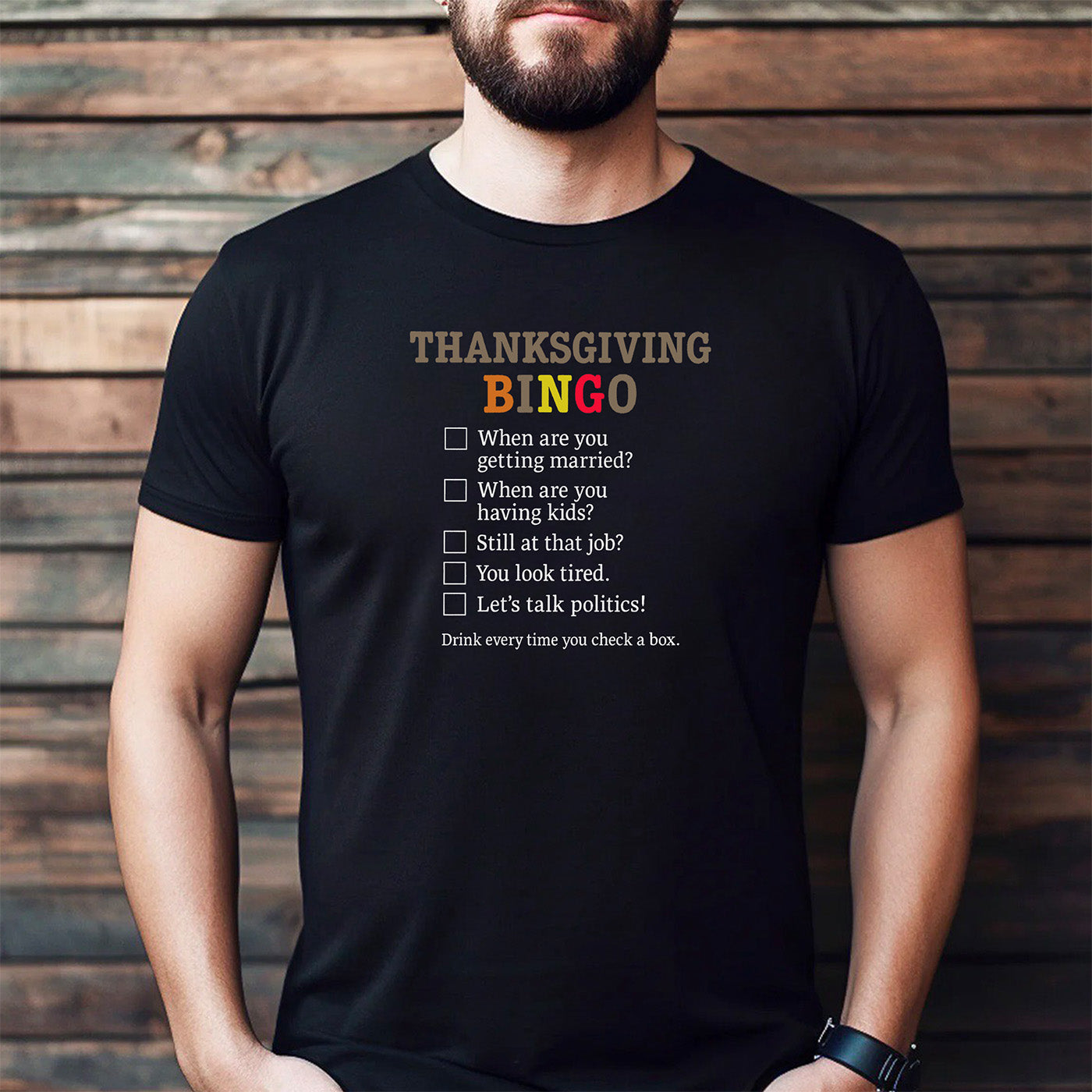 man wearing black t-shirt with thanksgiving bingo design showing humorous family question checklist
