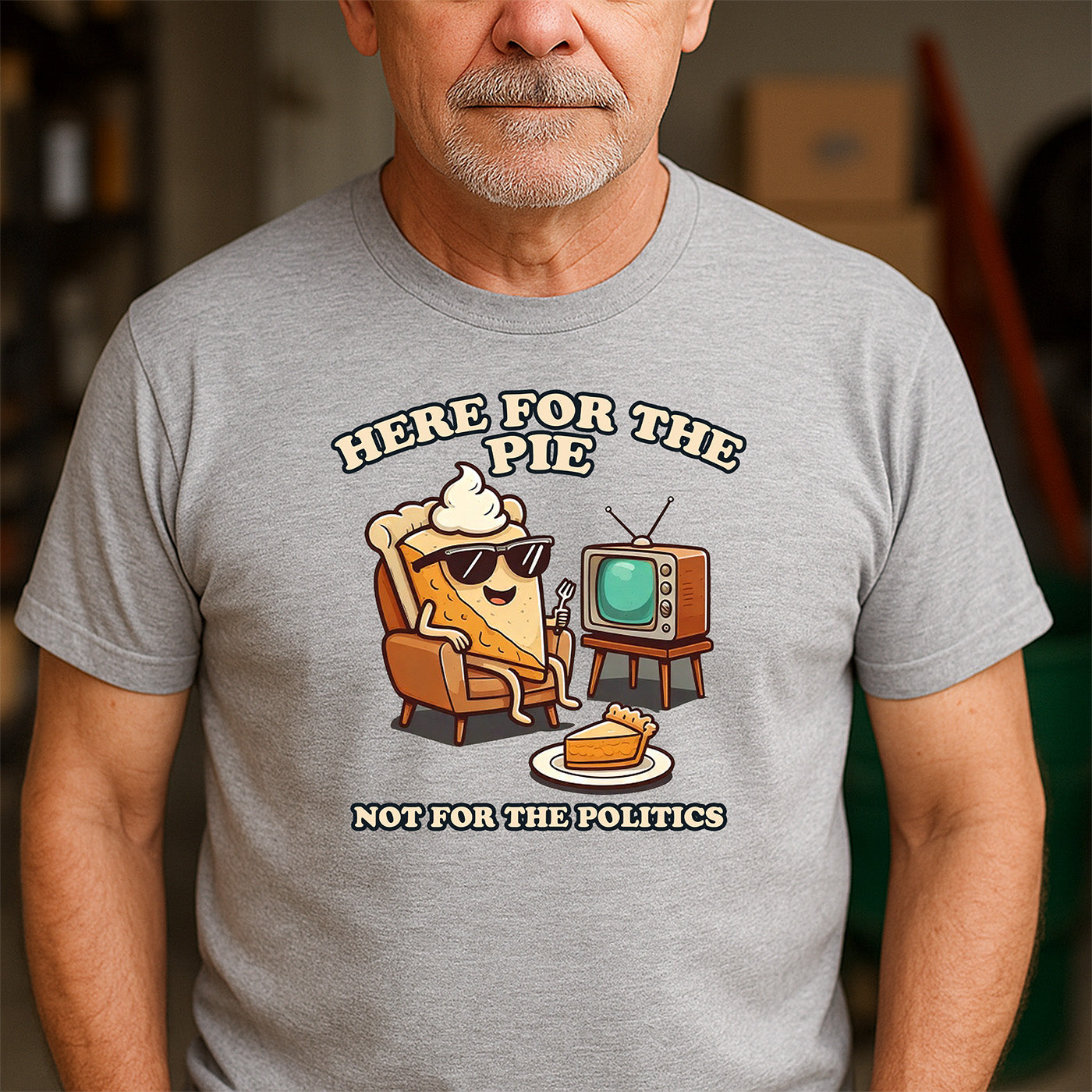 older man wearing gray t-shirt with cartoon pie slice relaxing and phrase here for the pie not for the politics