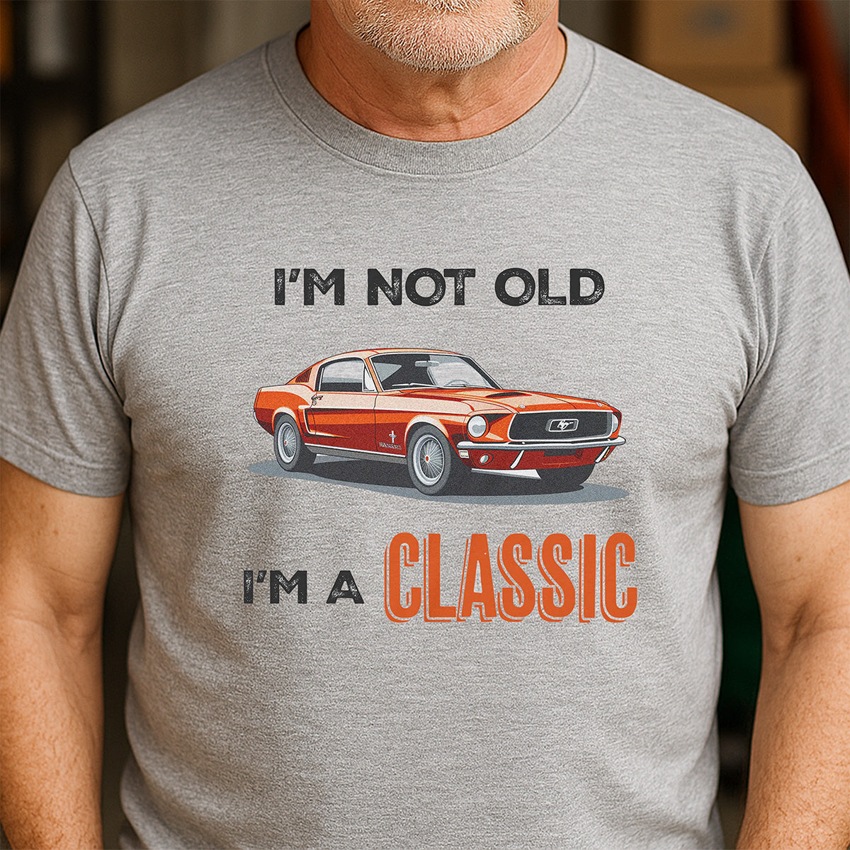 Man wearing gray classic car T-shirt with retro orange muscle car and I’m not old I’m a classic text