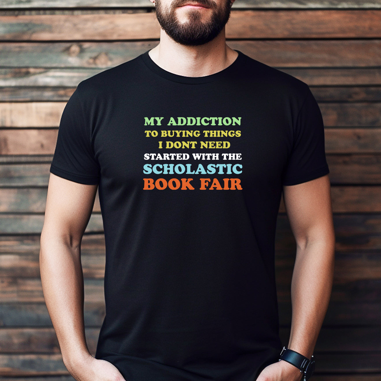 Man wearing a black Scholastic Book Fair addiction T-shirt with bold colorful lettering.