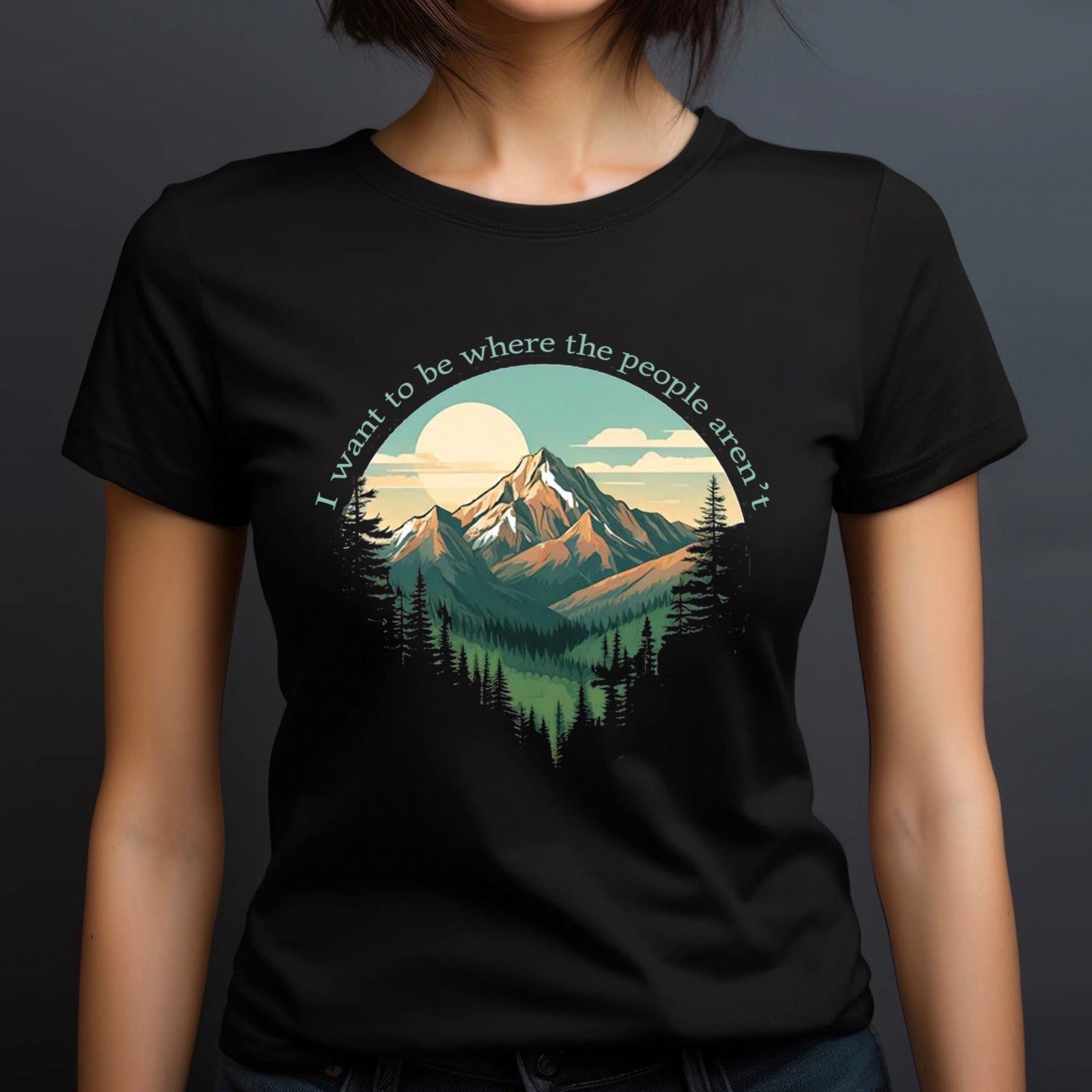 Woman in crew neck black t-shirt with mountain and forest design and text I want to be where the people aren't