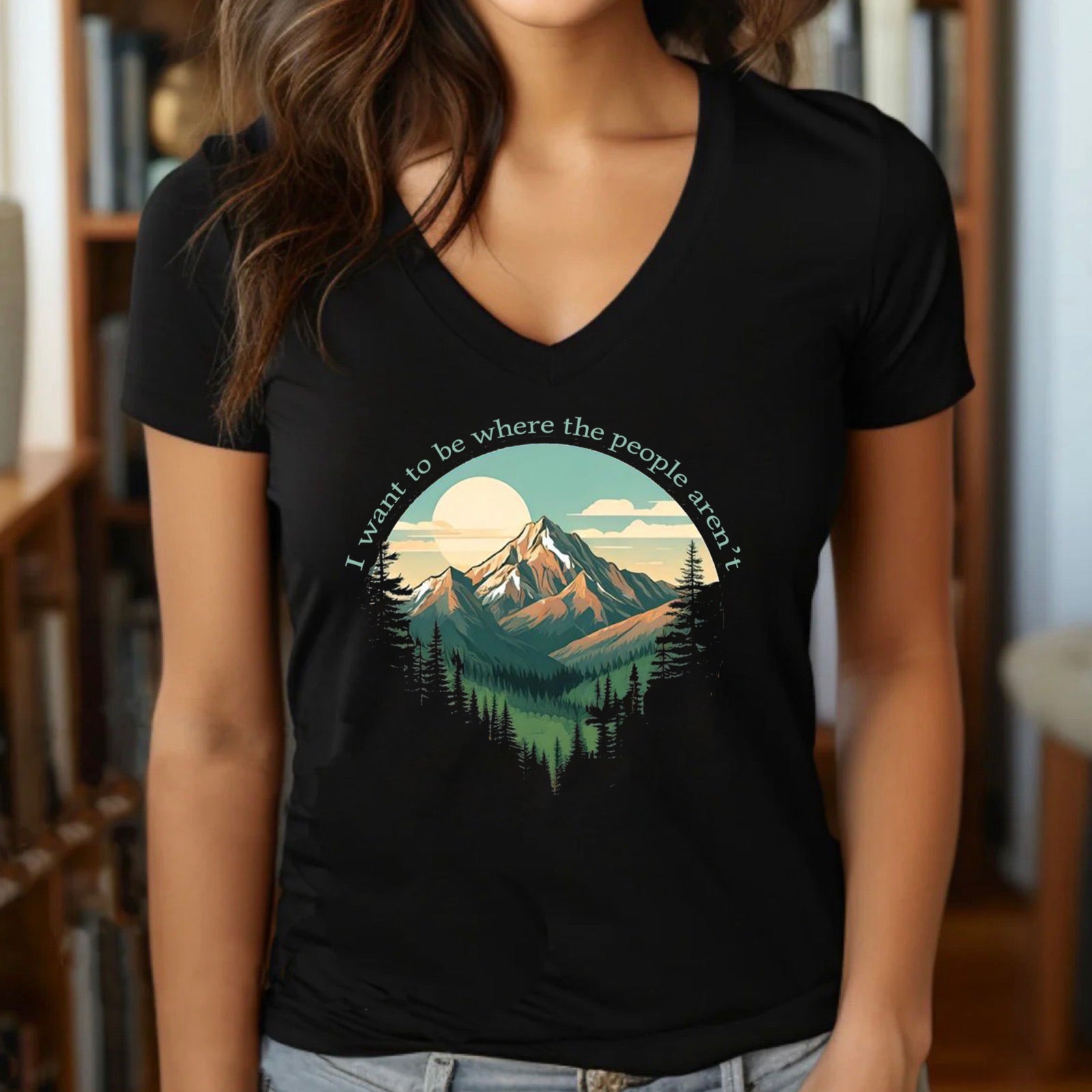 Woman wearing v-neck black t-shirt with scenic mountain print and quote I want to be where the people aren't