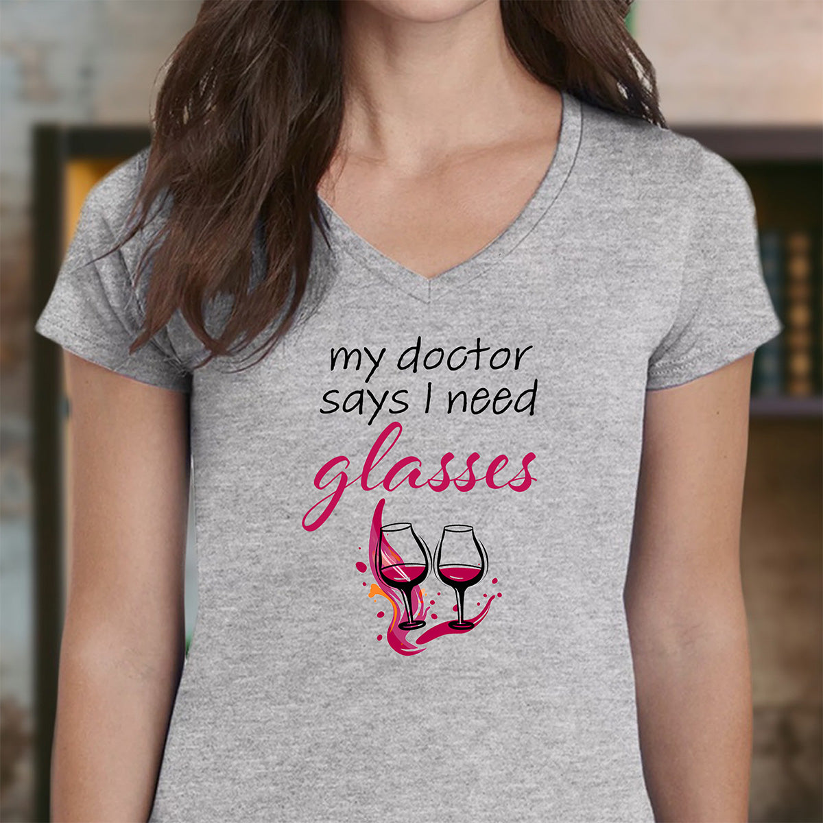 Woman in heather gray v-neck t-shirt with my doctor says I need glasses slogan and two wine glasses graphic