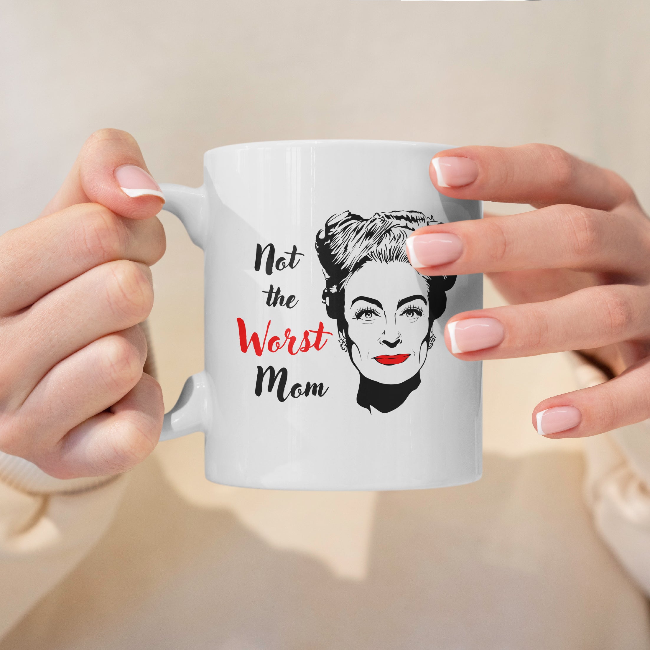 Lifestyle photo of white ceramic mug with illustration of Joan Crawford and text Not the Worst Mom.
