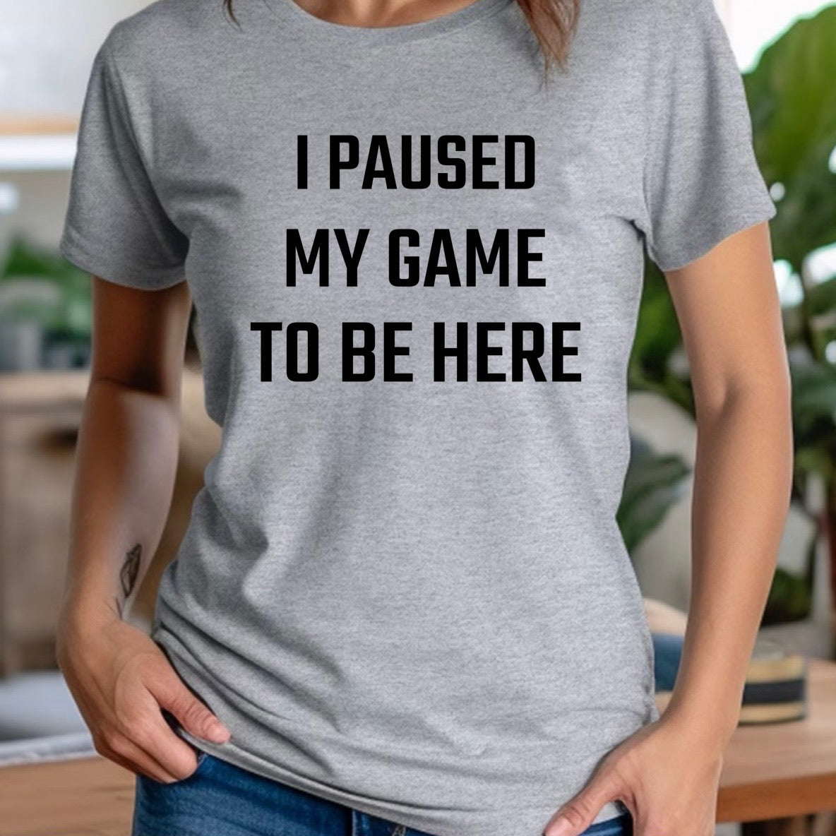 Woman wearing grey crew neck t-shirt with black text I Paused My Game To Be Here, gamer humor shirt