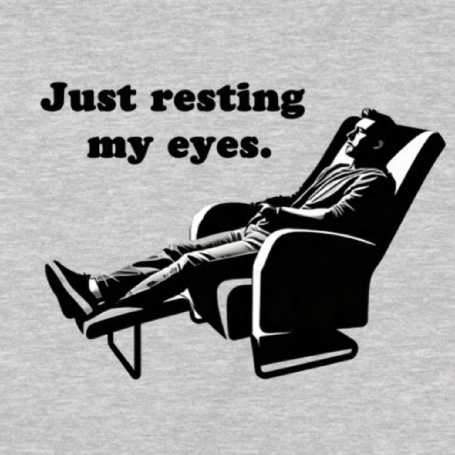 Closeup of grey shirt with Just resting my eyes text and reclining man graphic