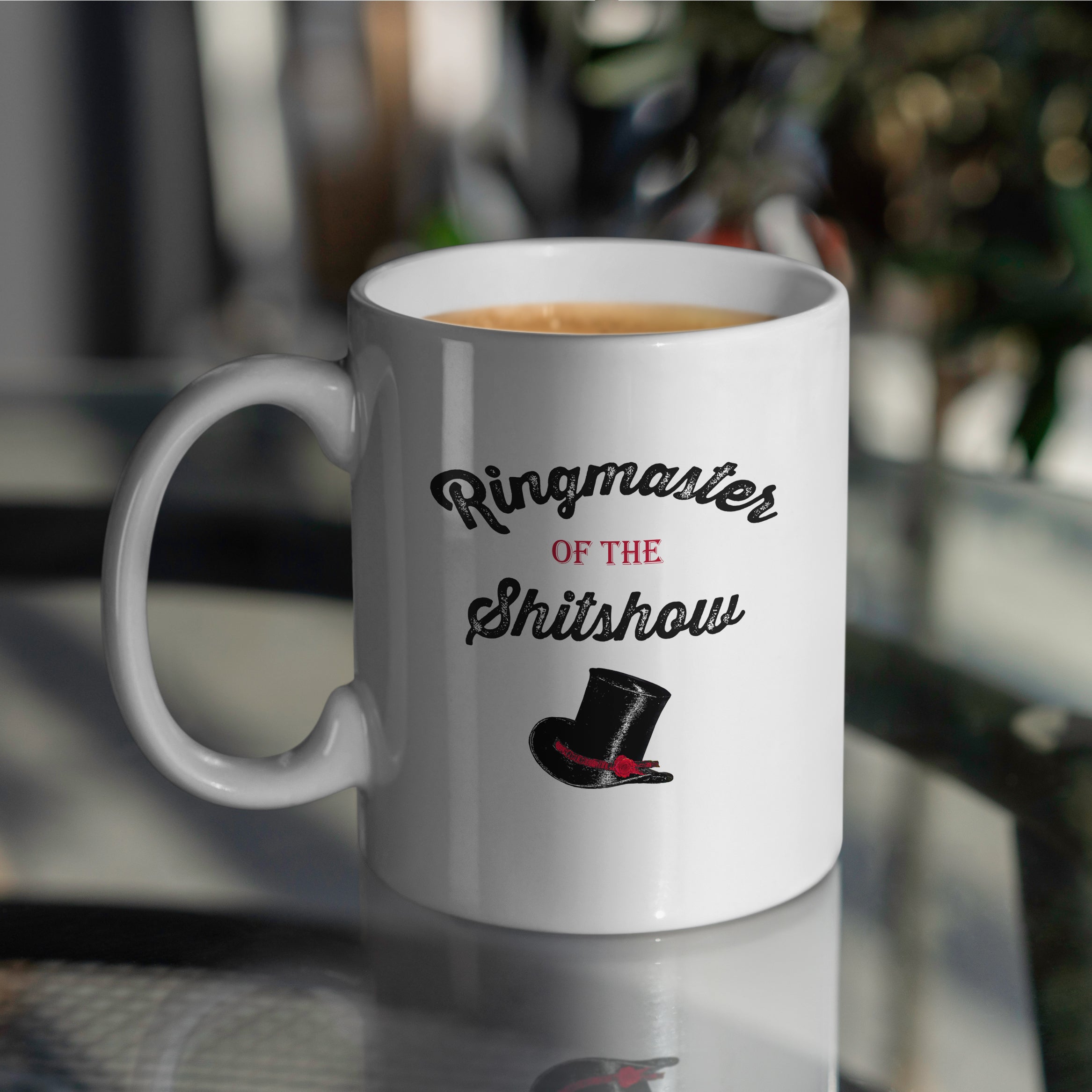 Ringmaster of the Shitshow design on white mug with top hat resting on table 15oz
