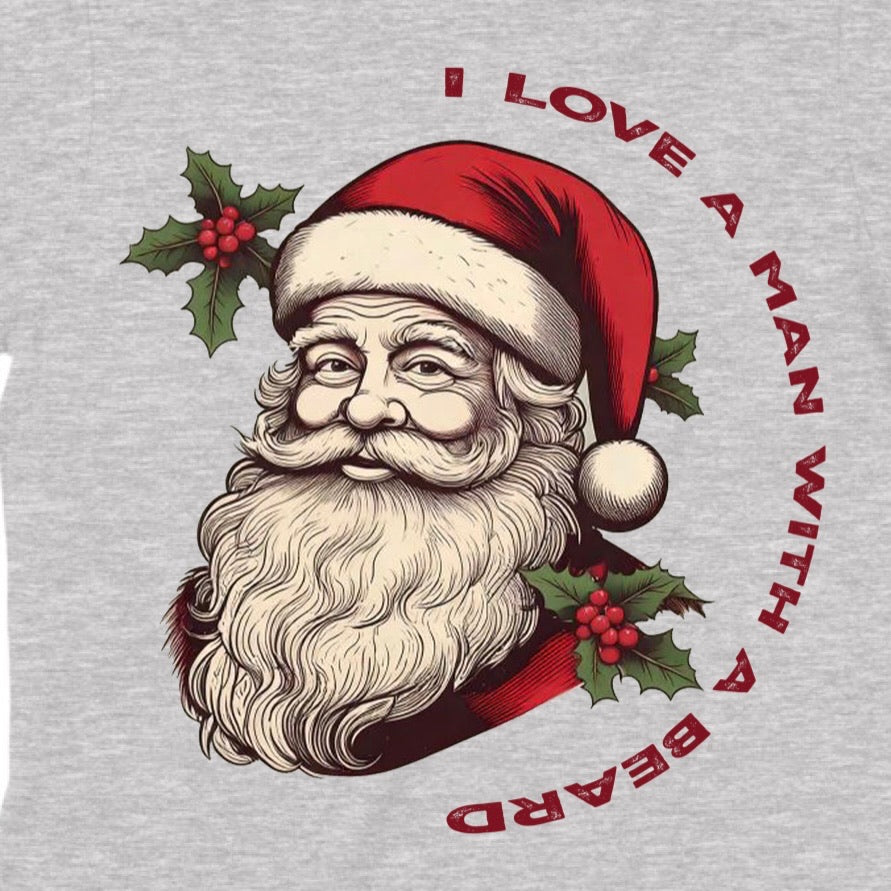 Closeup of Santa Claus graphic with red hat and holly on grey shirt reading I love a man with a beard