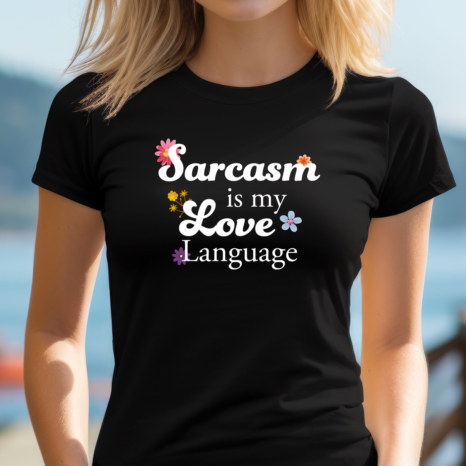 Woman outdoors in a fitted black T-shirt with floral typography that reads “Sarcasm is my love language.”