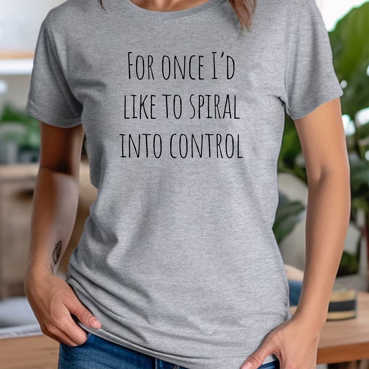 Woman in crew neck heather gray shirt with For once I'd like to spiral into control text; minimalist style
