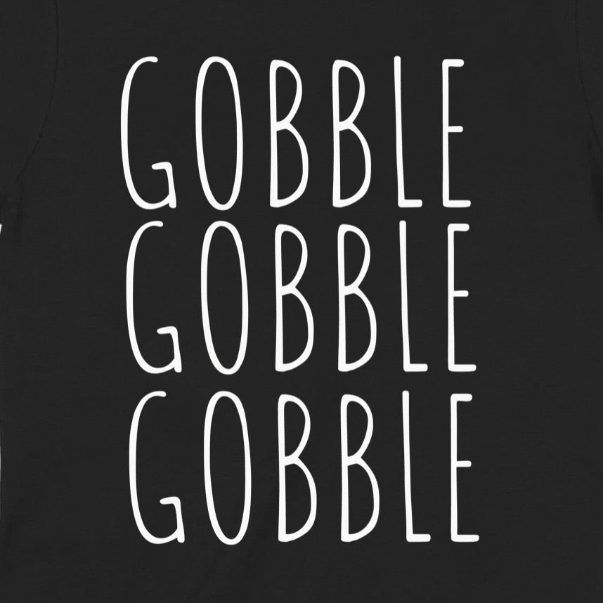 Closeup of white Gobble Gobble Gobble text design on black shirt