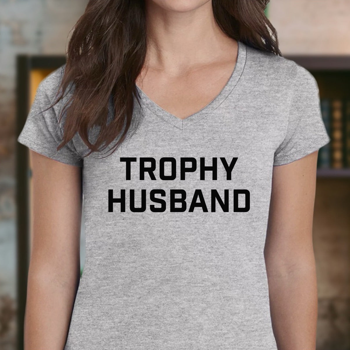 Woman wearing gray v-neck Trophy Husband t-shirt with bold black print