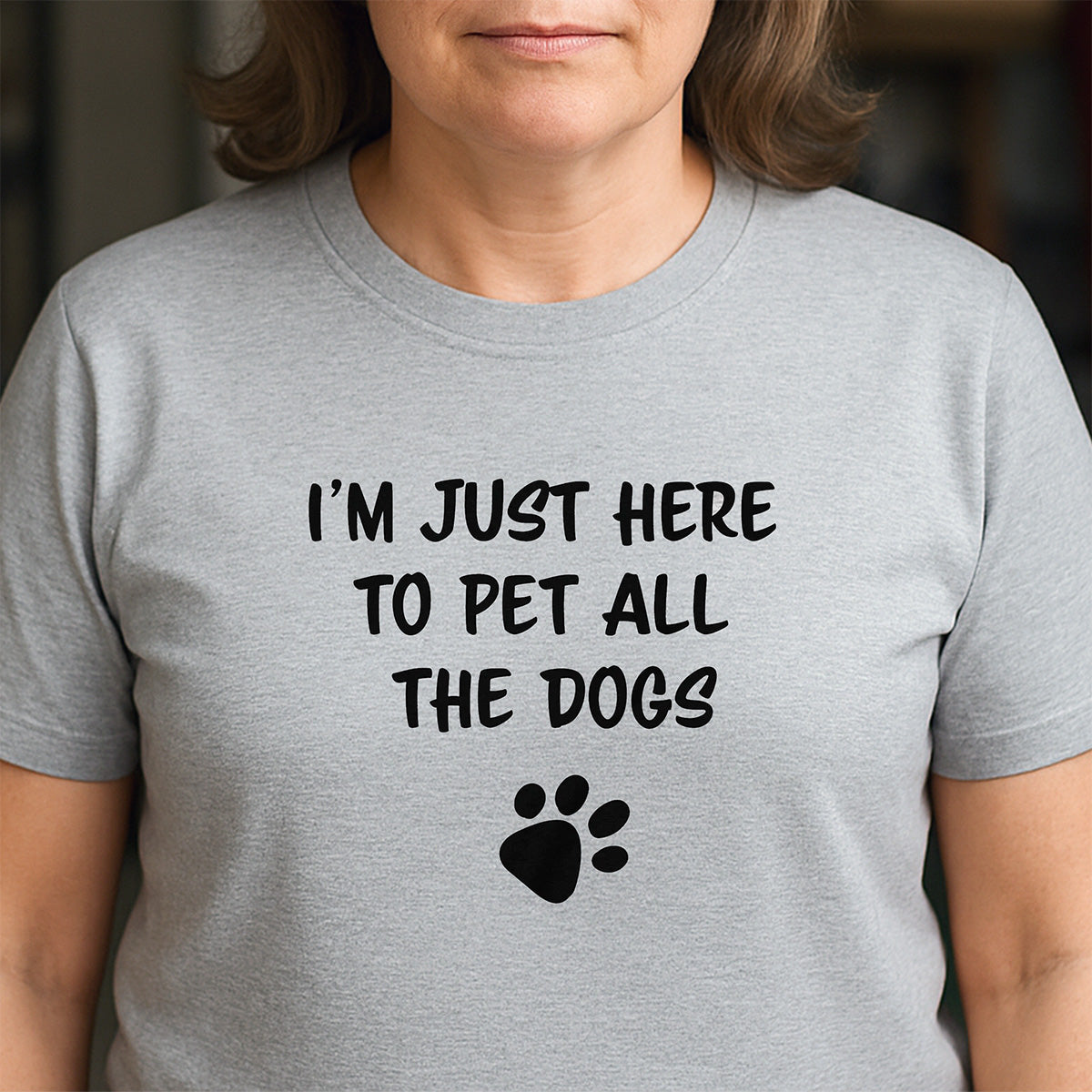 Woman in gray crew neck t-shirt with dog paw print design saying I’m just here to pet all the dogs