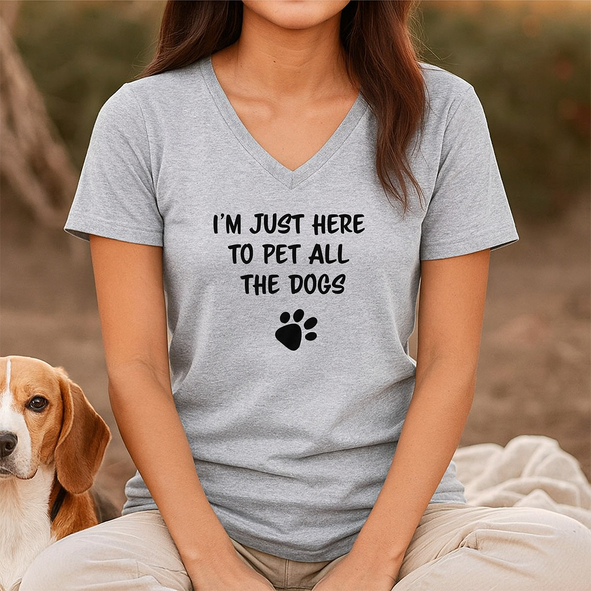 Woman wearing gray v-neck t-shirt with playful dog paw print and text I’m just here to pet all the dogs
