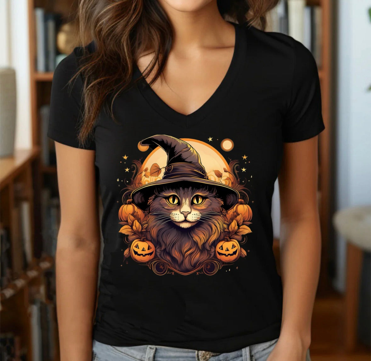 Woman vneck modeling Halloween shirt with black cat in witch hat design, surrounded by pumpkins and full moon