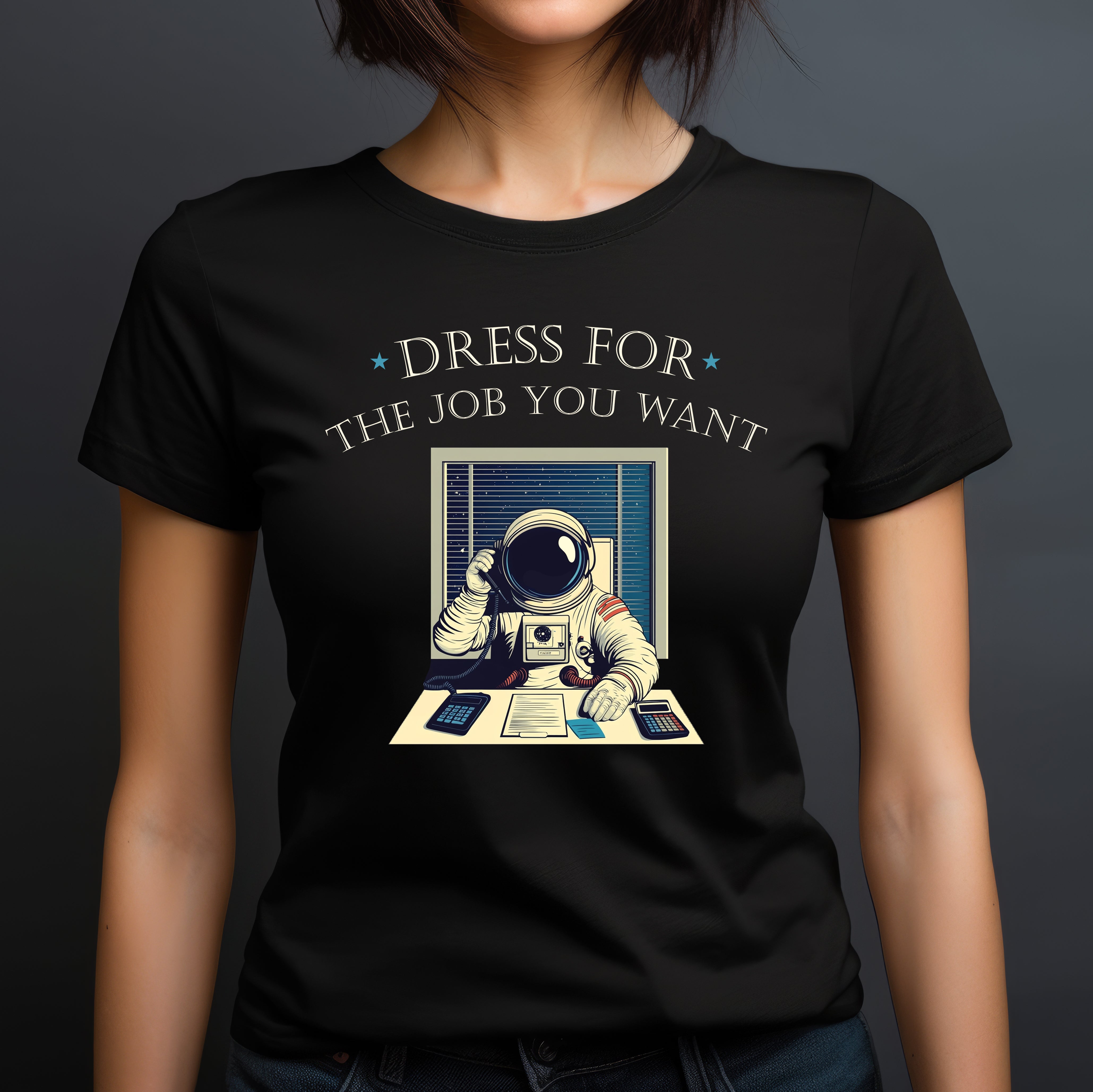 Woman in black crew neck t-shirt with astronaut at desk graphic and text dress for the job you want