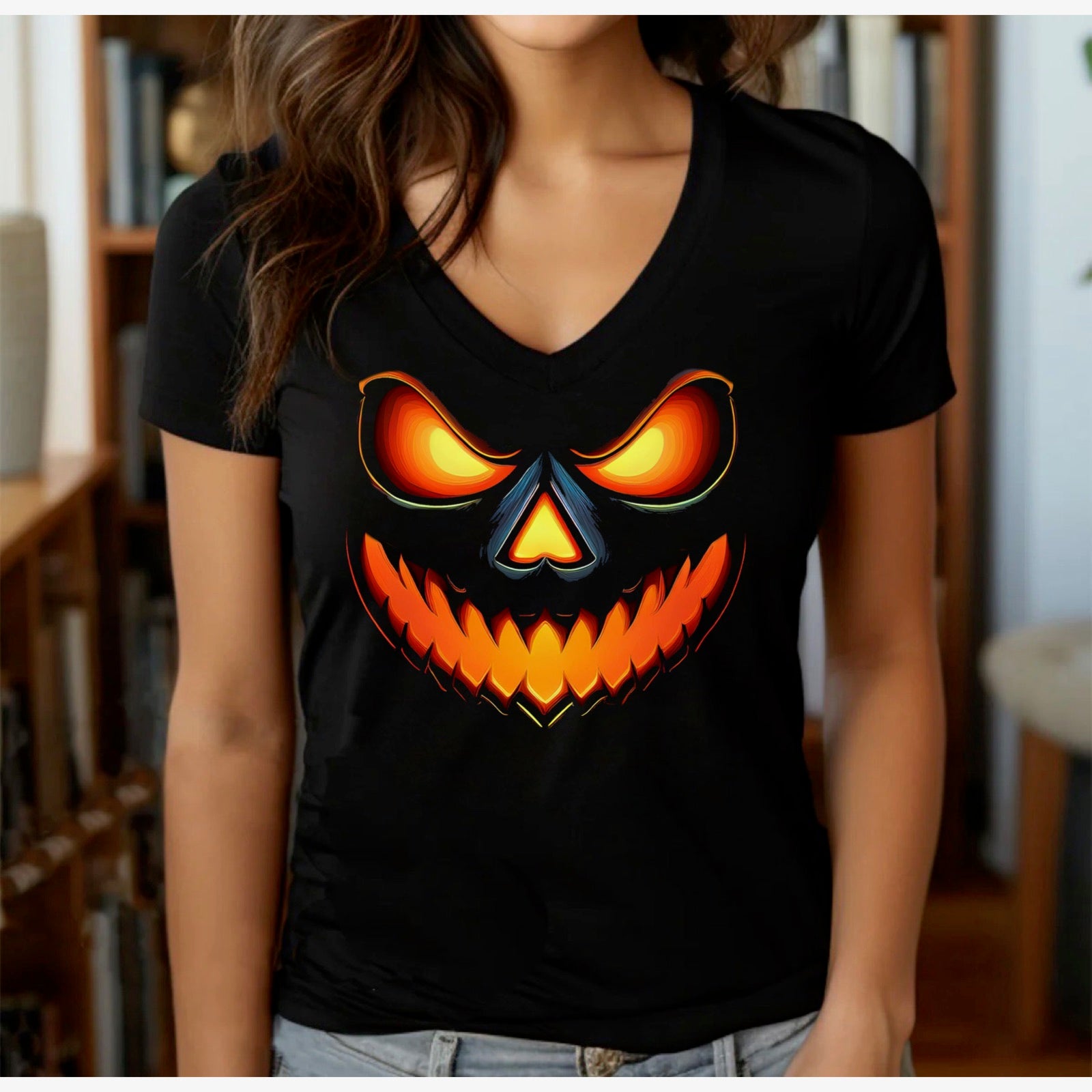 Women’s black v-neck Halloween t-shirt with glowing jack-o-lantern face in casual indoor setting