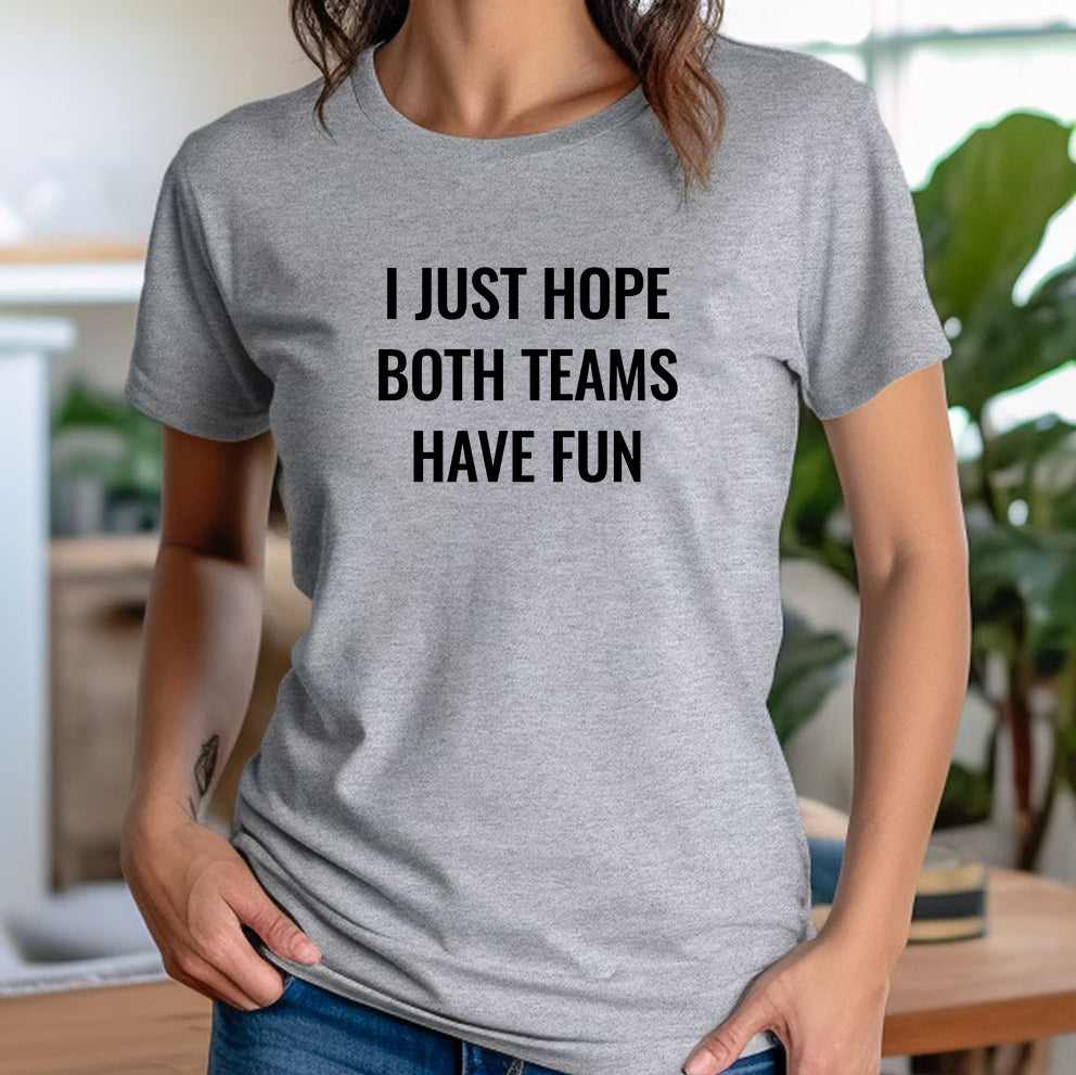 Woman in casual indoor setting wearing a gray t-shirt with the phrase "I Just Hope Both Teams Have Fun."