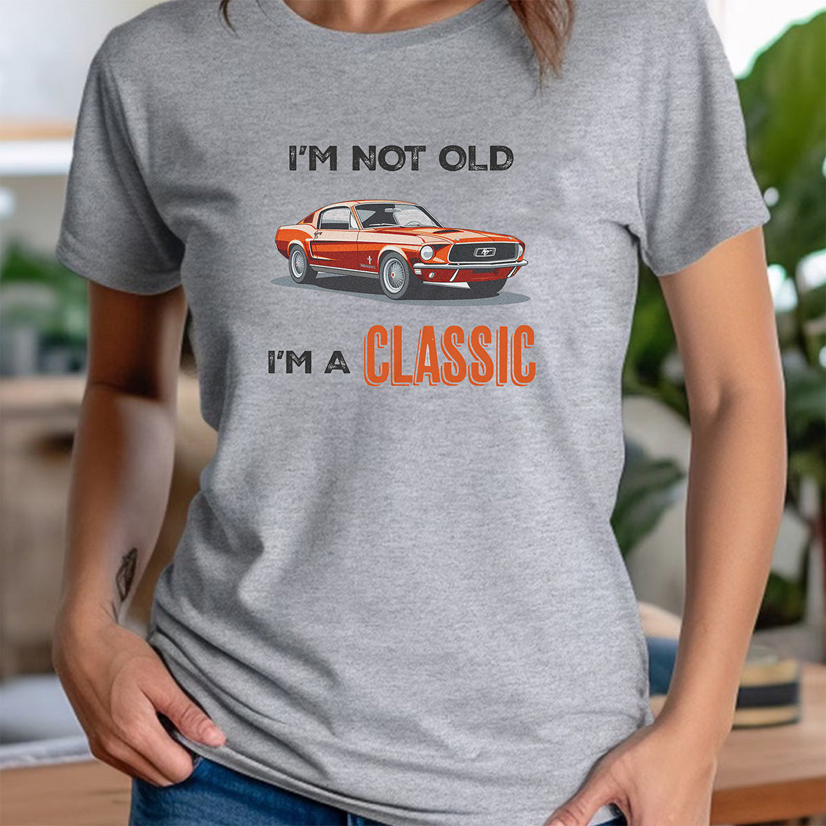 Woman wearing gray crewneck tee featuring orange classic car and I’m not old I’m a classic design