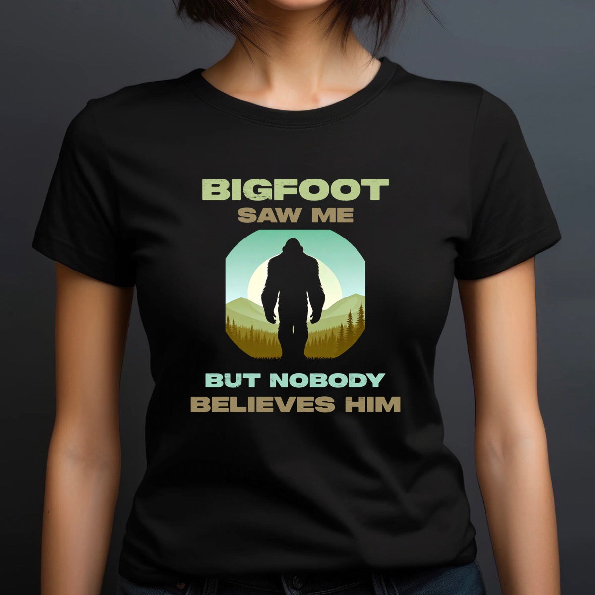 Woman in black crewneck shirt with Bigfoot saw me but nobody believes him text and mountain silhouette design